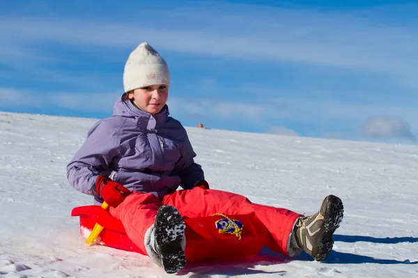 Een meisje in de sneeuw glijden — Stockfoto
