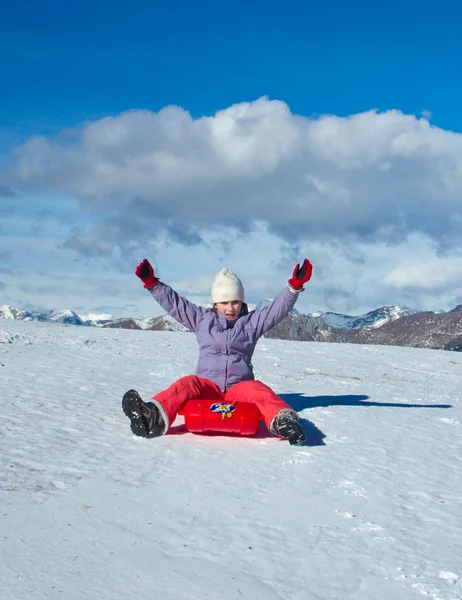 Een meisje in de sneeuw glijden — Stockfoto