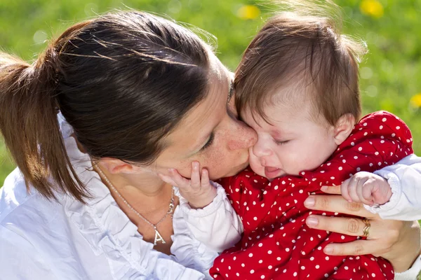 Мать целует ребенка в парке — стоковое фото