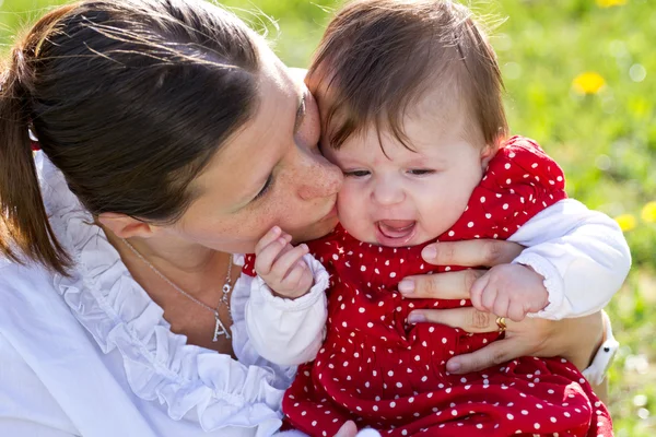 Matka líbání baby v parku — Stock fotografie