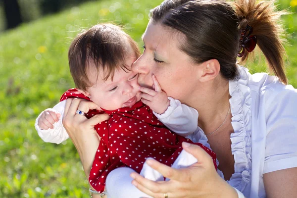Moeder kussen baby in het park — Stockfoto