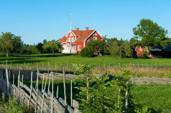 Červené dřevěný dům uprostřed zelené louky ve Švédsku — Stock fotografie