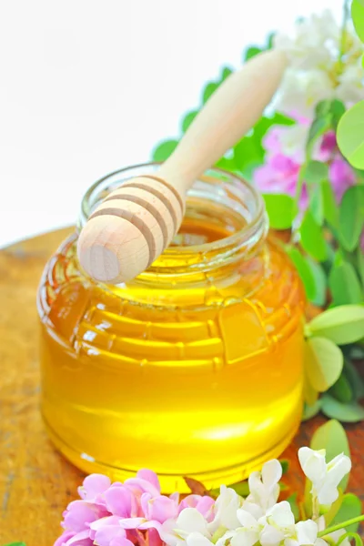 Glazen pot vol van honing en stok met acacia roze en witte fl — Stockfoto