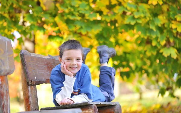 Boy laying down on a bench — Stock Photo, Image