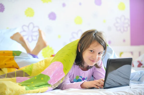 Teen flicka i sängen ser på laptop — Stockfoto