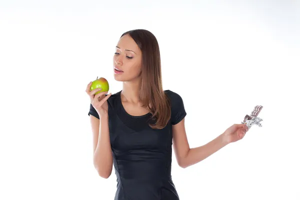 Девушка держит шоколад и яблоко в руках на белом — стоковое фото