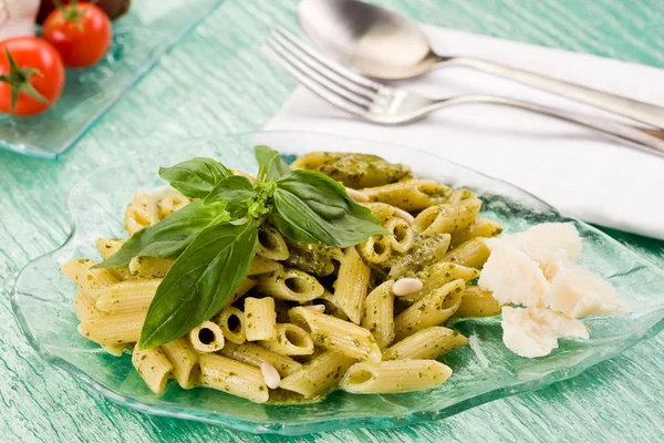 Pasta with pesto on green glass table — Stock Photo, Image