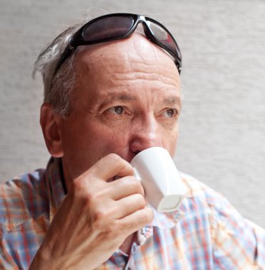 Old man drinking cup of coffee