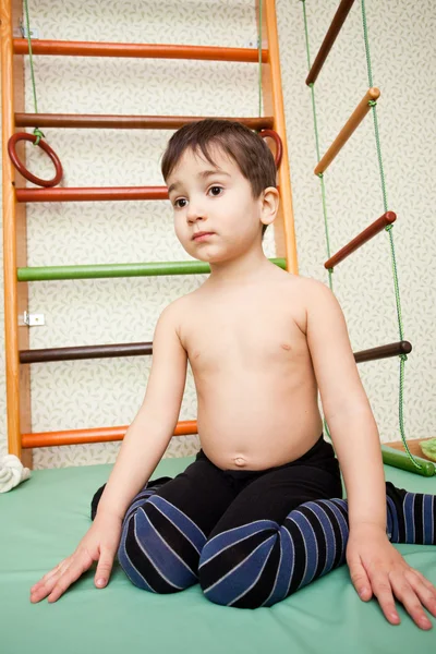 Child sitting againast home sport gym — Stock Photo, Image