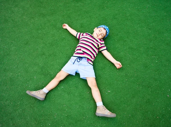 Chlapec na plastové zelené trávy — Stock fotografie