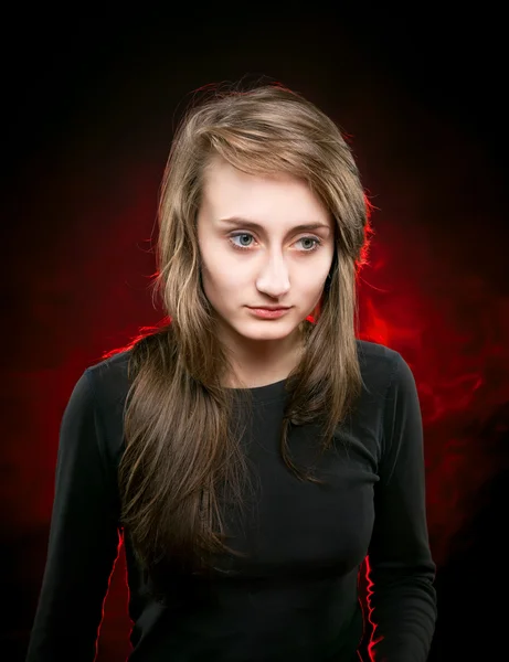 Chica en negro iluminado por la luz trasera roja — Foto de Stock
