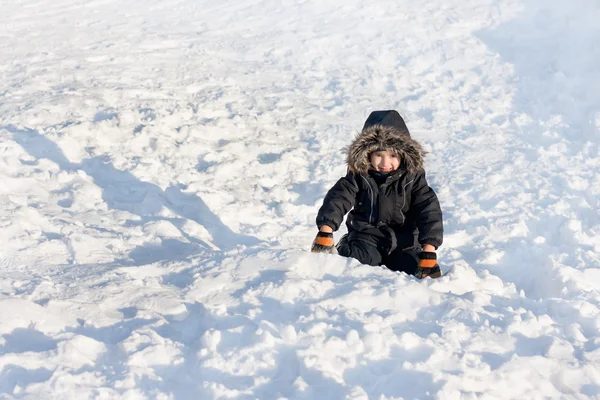 Ung pojke sitter på snön — Stockfoto