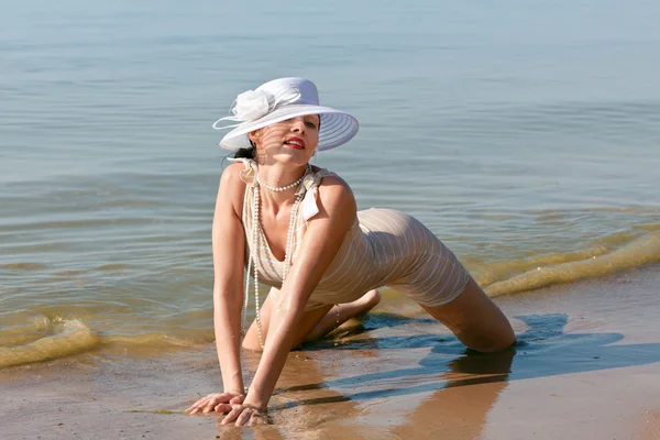 Frau mit weißem Hut posiert gegen das Meer — Stockfoto