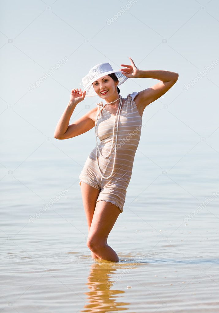 Woman in white hat posing against the sea