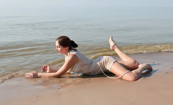 Kvinna liggande i vattnet på stranden — Stockfoto