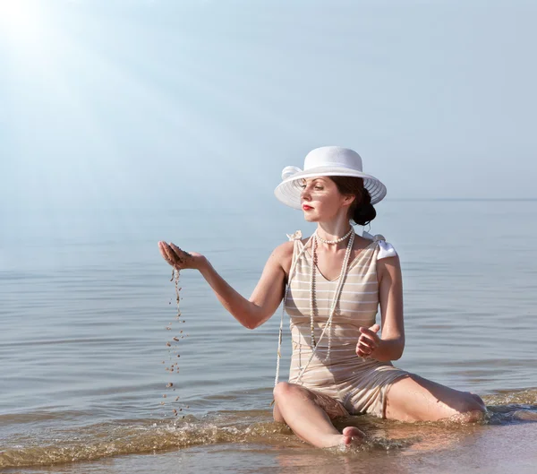 Женщина в белой шляпе позирует против моря — стоковое фото