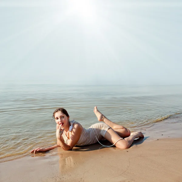 Frau mit weißem Hut posiert gegen das Meer — Stockfoto