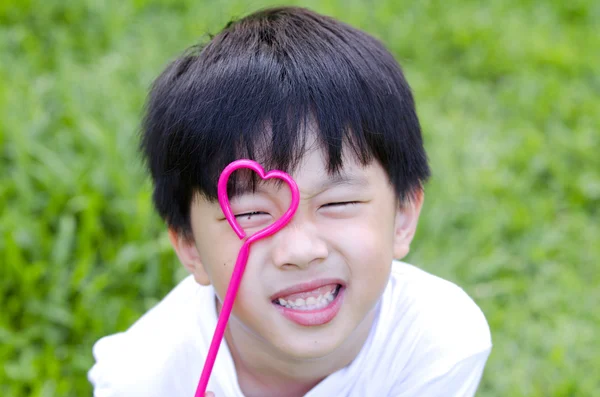 Χαριτωμένο Ασίας αγόρι που κατέχουν ένα σχήμα καρδιάς για το μάτι του — Φωτογραφία Αρχείου