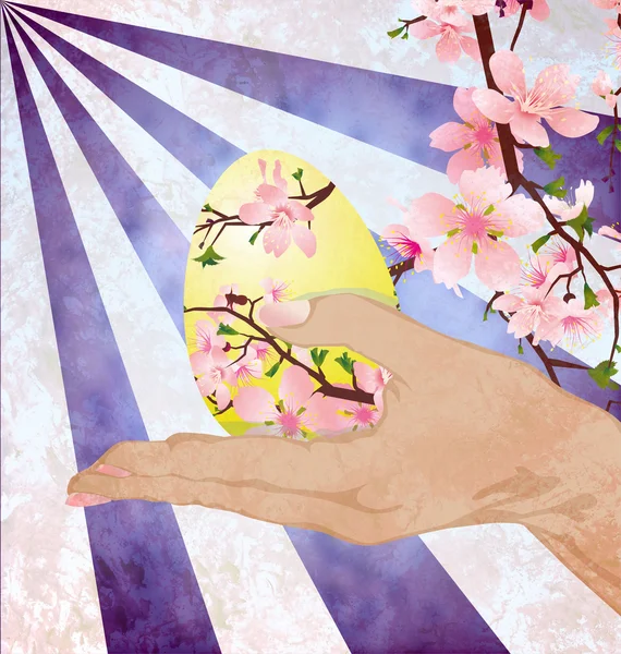 Mano con uovo di Pasqua decorato con fiori di albero rosa su grunge — Foto Stock
