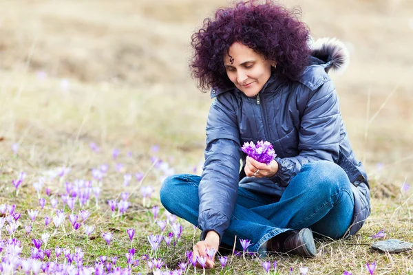 Kudrnatá zrzka žena trhá crocus květiny — Stock fotografie