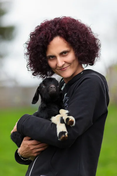 Mujer sosteniendo una cabra bebé — Foto de Stock