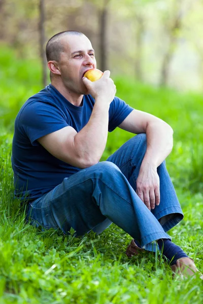Hombre comiendo una manzana al aire libre — Foto de Stock
