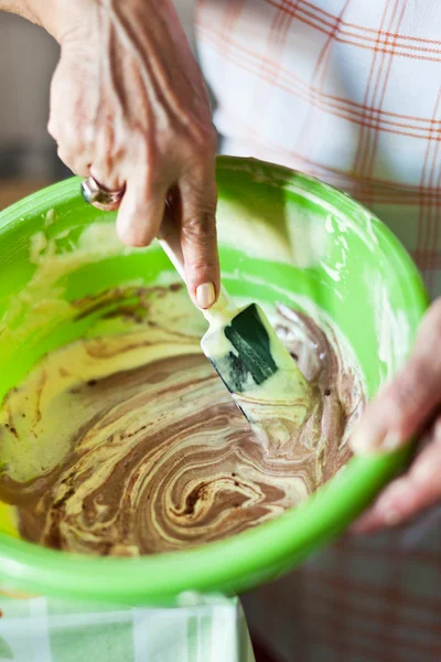 Руки пожилой женщины мешают какао-крем с лопаткой — стоковое фото