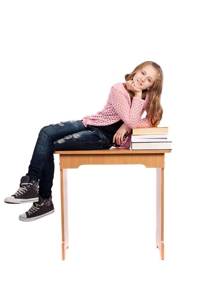 Školačka sedí na stole s knihami — Stock fotografie