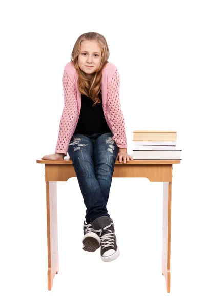 Schoolgirl sitting on desk with books — Stock Photo, Image