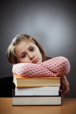 Unhappy schoolgirl with a stack of books clipart