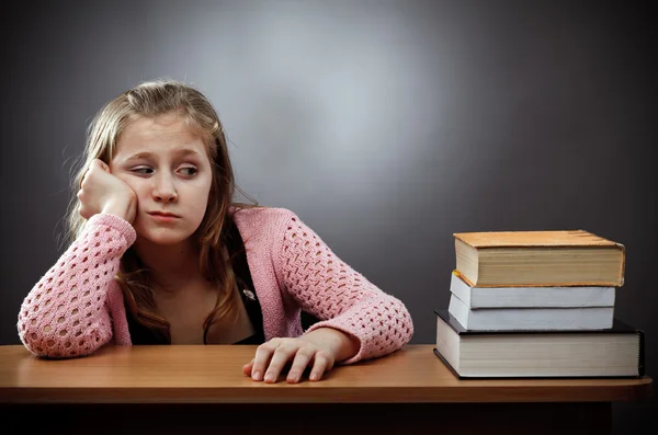 Unglückliches Schulmädchen mit einem Stapel Bücher — Stockfoto