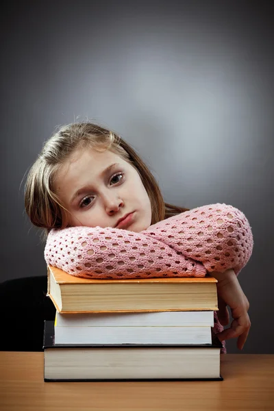 Unglückliches Schulmädchen mit einem Stapel Bücher — Stockfoto