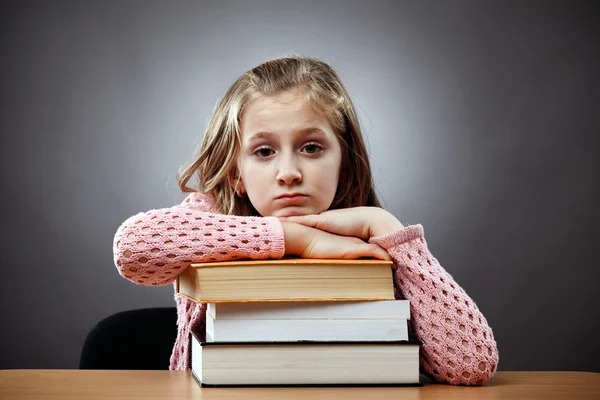 Unglückliches Schulmädchen mit einem Stapel Bücher — Stockfoto