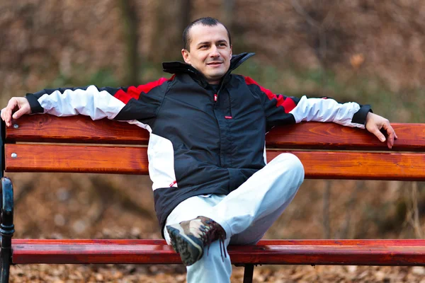 Jeune homme sur un banc dans le parc — Photo