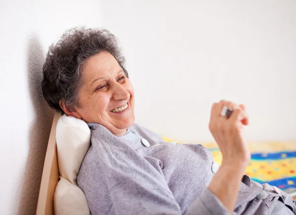 Old woman sitting on bed — Stock Photo, Image