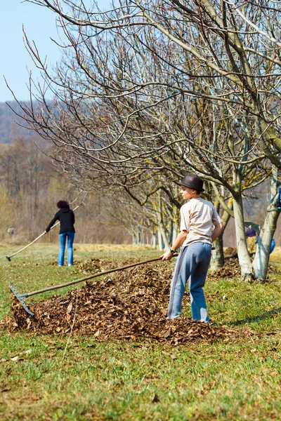 Jongen en zijn moeder voorjaarsschoonmaak de tuin — Stockfoto