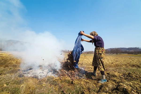 Senior landelijke vrouw branden gevallen bladeren — Stockfoto