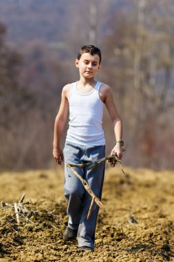 Boy walking on plow soil clipart