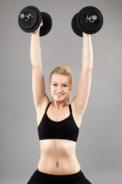Athletische junge Frau trainiert mit Gewichten — Stockfoto