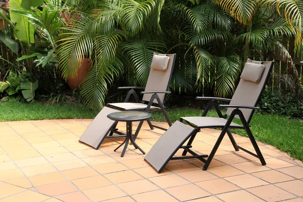Zwei Liegestühle neben einem Pool umgeben von tropischem Garten — Stockfoto