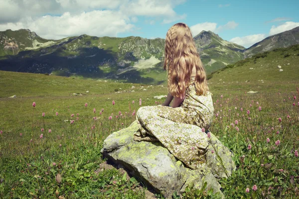 Beautiful young woman in mountains on a meadow — Stock Photo, Image