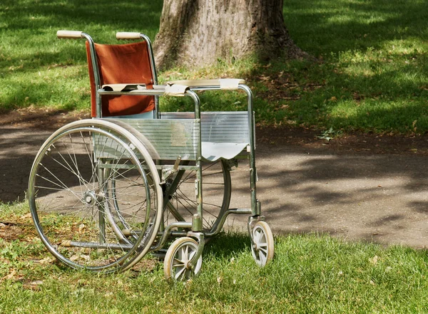Cadeira de rodas abandonada velha no parque — Fotografia de Stock