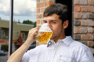 Young man binging on beer clipart