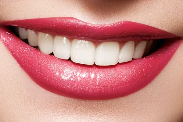 Närbild glad kvinna leende med friska vita tänder, ljus magenta läppar make-up. kosmetologi, tandvård och skönhet vård. makro kvinna leende mun Stockbild