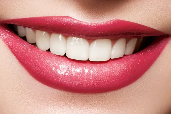 Close-up sorriso feminino feliz com dentes brancos saudáveis, maquiagem lábios magenta brilhante. Cosmetologia, odontologia e cuidados de beleza. Macro da boca sorridente da mulher Imagem De Stock