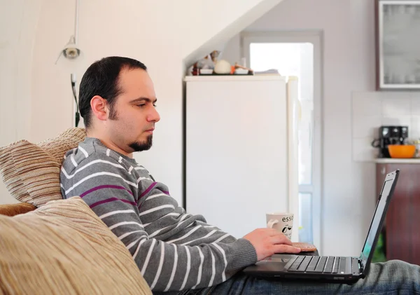 Młody człowiek z laptopem w domu — Zdjęcie stockowe