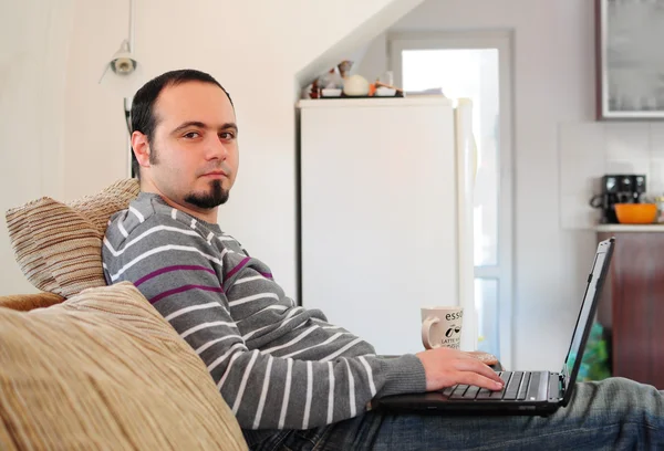 家にノートパソコンを持つ若い男 — ストック写真