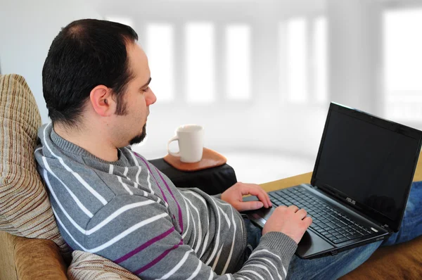 家にノートパソコンを持つ若い男 — ストック写真
