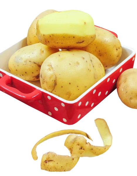 Raw potatoes in red tray and potato peels, isolated — Stock Photo, Image