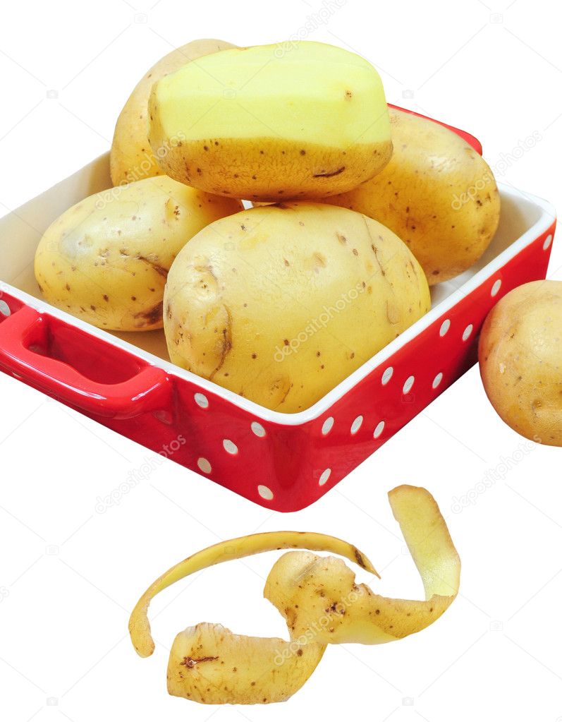 Raw potatoes in red tray and potato peels, isolated